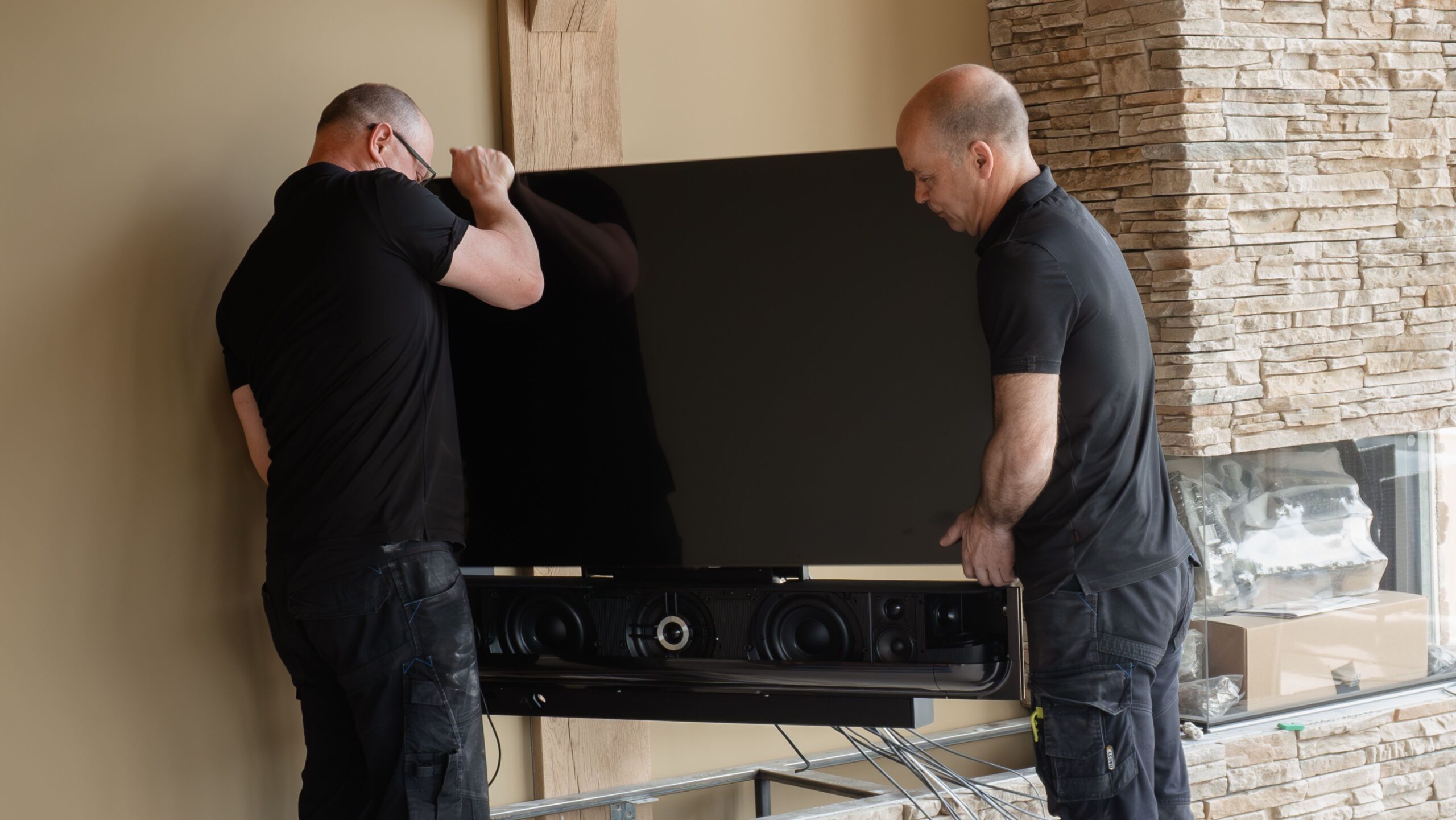 Technici installeren een Bang & Olufsen televisie met soundbar bij de klant thuis.