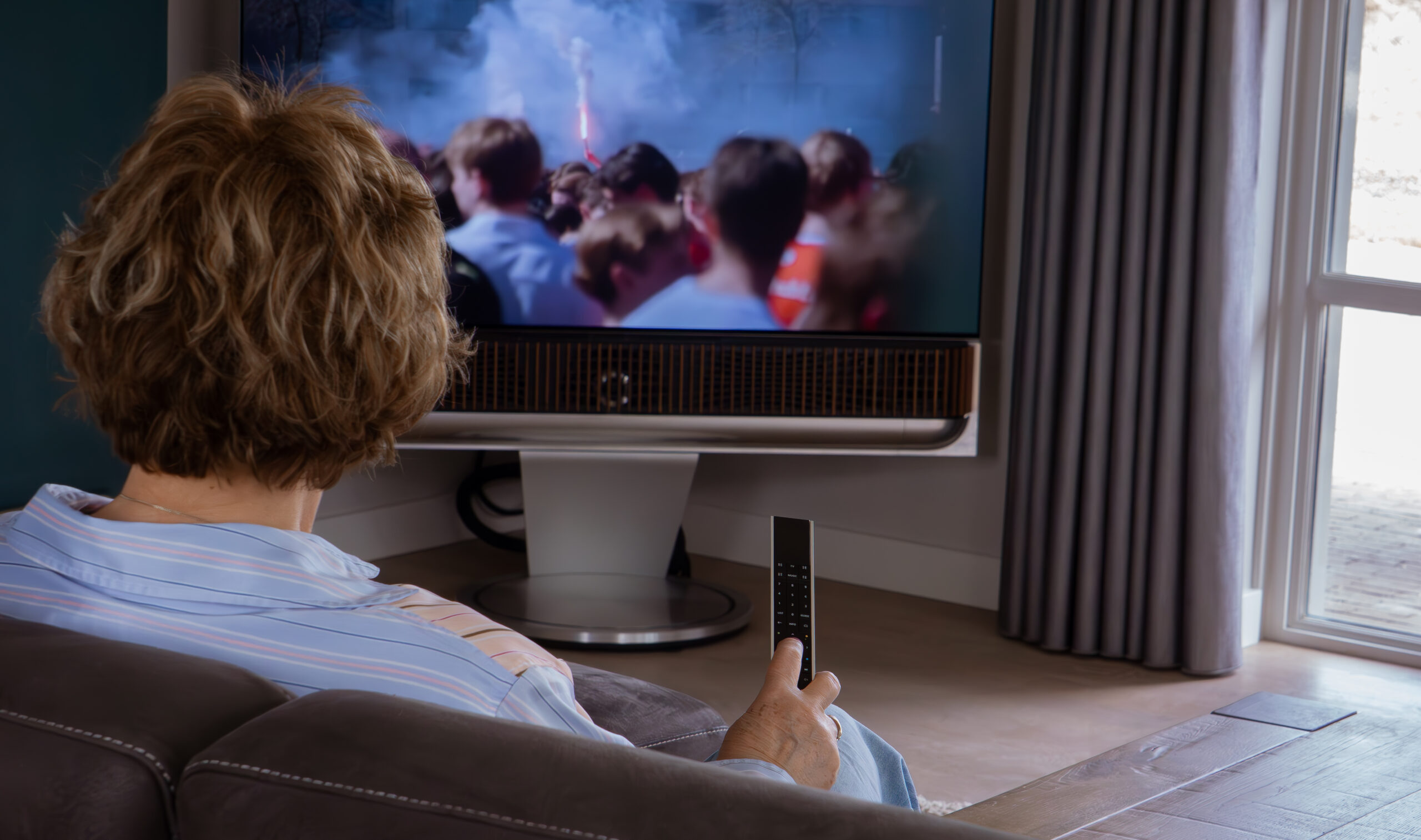 Vrouw kijkt naar de Beovision Theatre met een Beoremote One in de hand