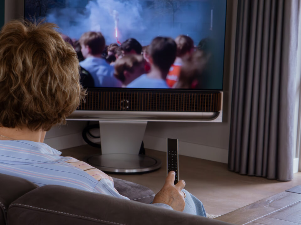 Vrouw kijkt naar de Beovision Theatre met een Beoremote One in de hand