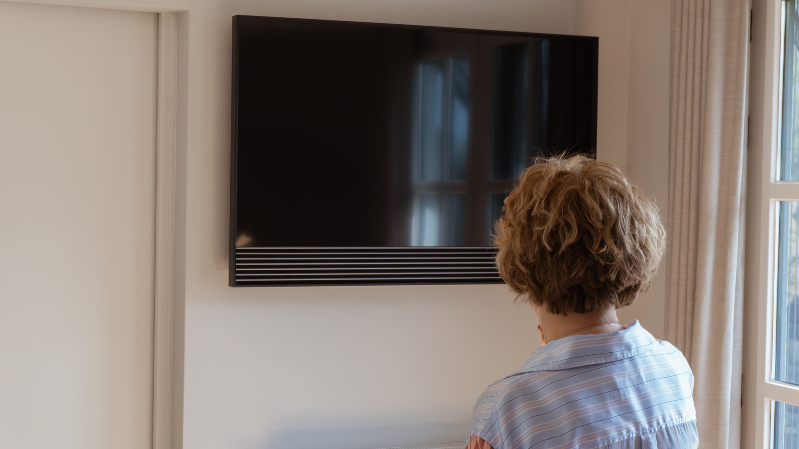 Vrouw kijkt naar een Beovision Horizon aan de muur