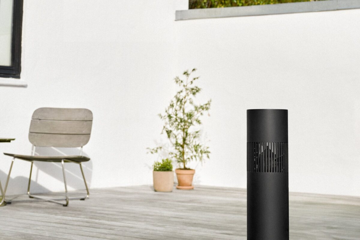 Zwarte Beosound Bollard op een terras met tuinstoel en planten